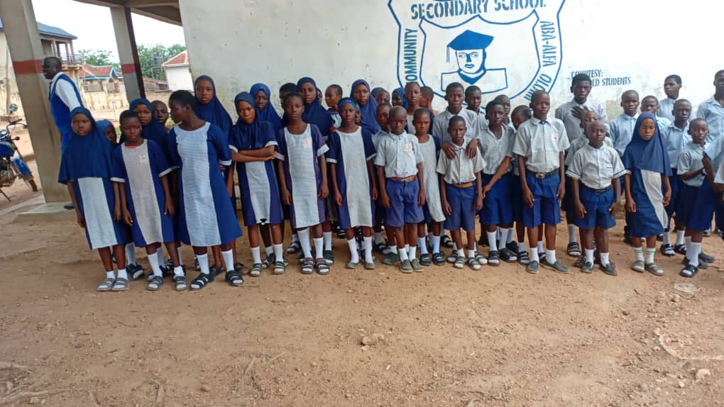 Secondary school students holding donated notebooks outside their school